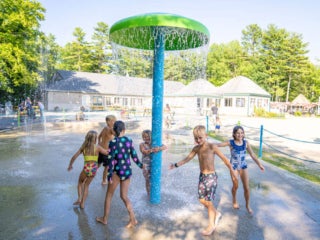 Kids running around the splash pad at Point Sebago Resort in Maine.