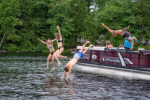 Guest jumping off the boat on Sebago Lake at Point Sebago Resort in Maine.