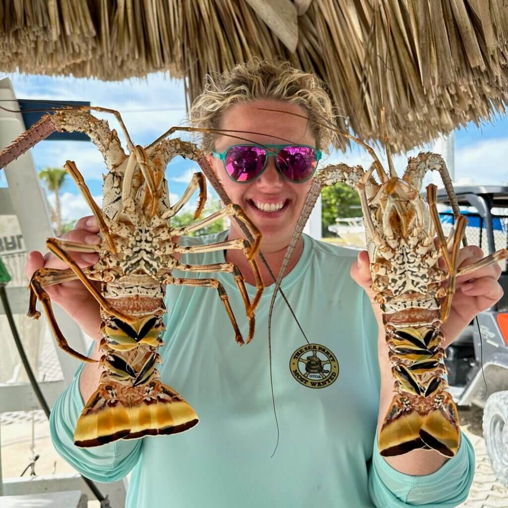 A woman holds up two spiny lobsters caught off the coast of Big Pine Key in Florida.