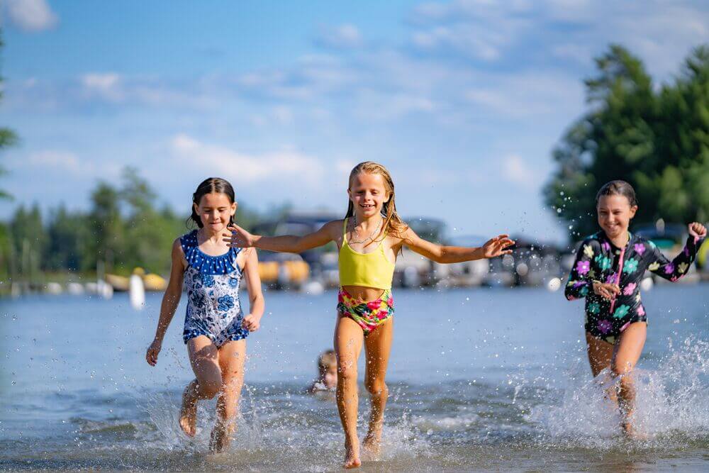 Kids running along the shoreline of Sebago Lake in Casco, Maine.