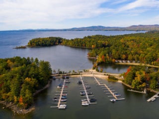 Aerial view of lakefront trees starting to change colors in the beginning of fall at Point Sebago Resort