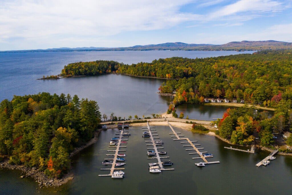 Aerial view of lakefront trees starting to change colors in the beginning of fall at Point Sebago Resort