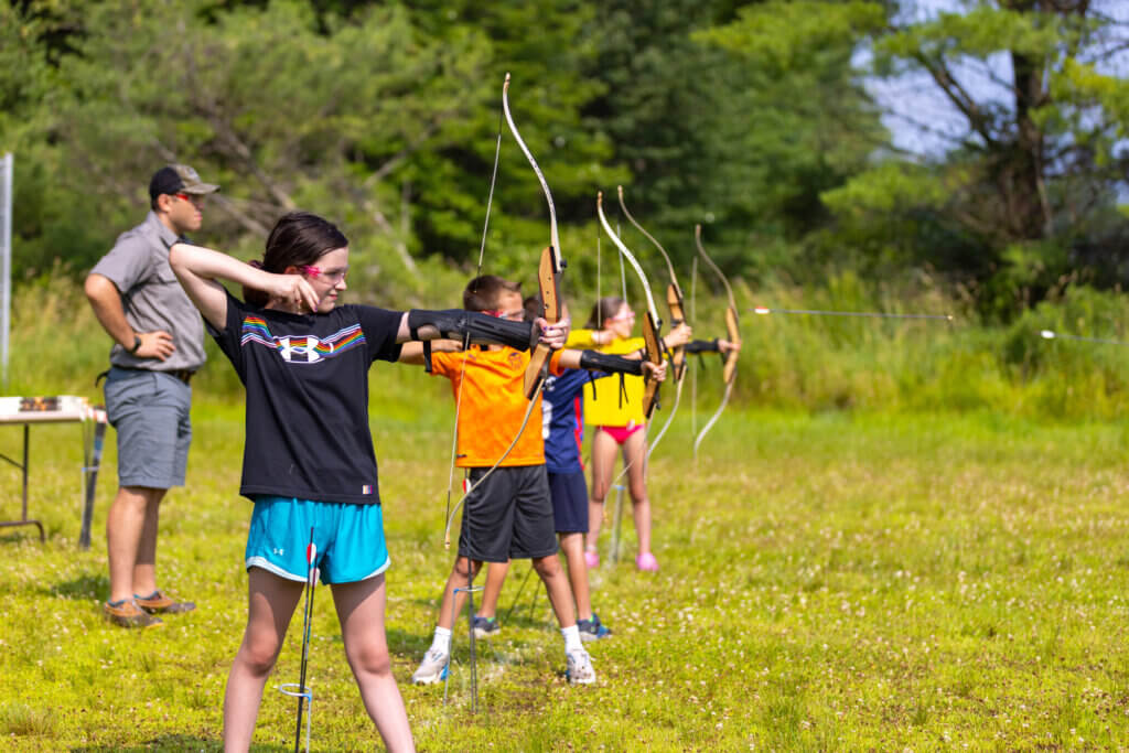 kids lined up with bow and arrows at archery activity at Point Sebago