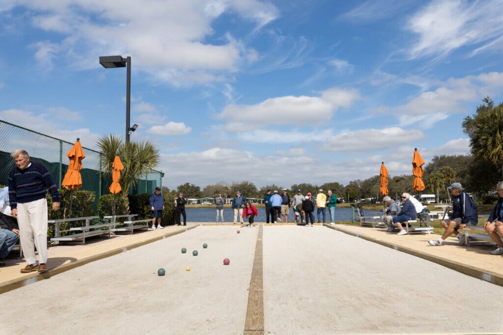 Residents at camelot east playing bocce ball at the bocce court facility overlooking the lake.