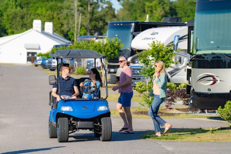 Two people in a golf cart picking up another couple at their RV site at CreekFire RV Resort in Savannah.