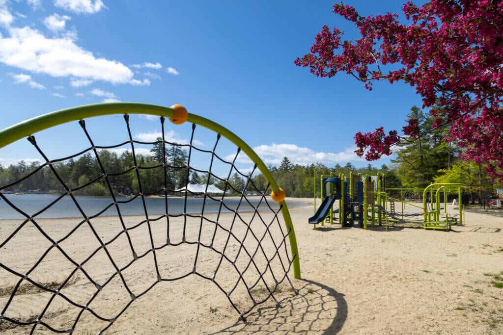Empty playground set sitting on the beach at Sebago Lake