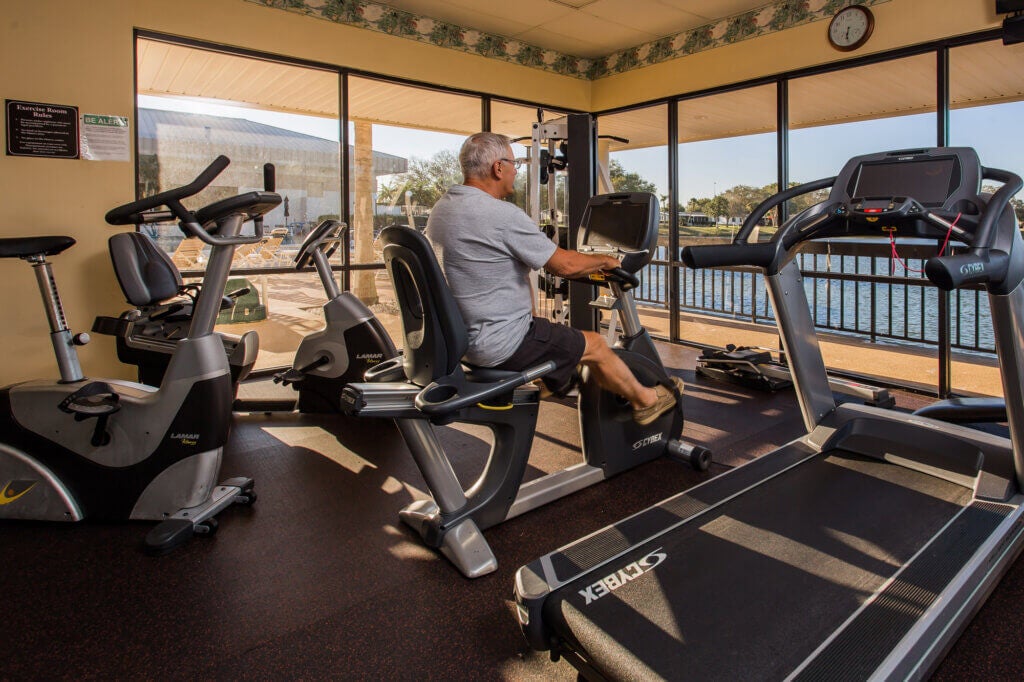 Senior riding the elliptical machine in the fitness center at camelot east village