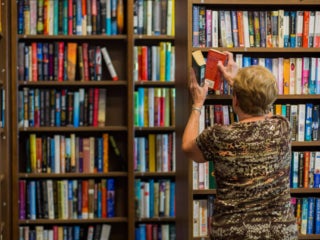 Resident putting a book on the bookshelf at Rolling Greens Village