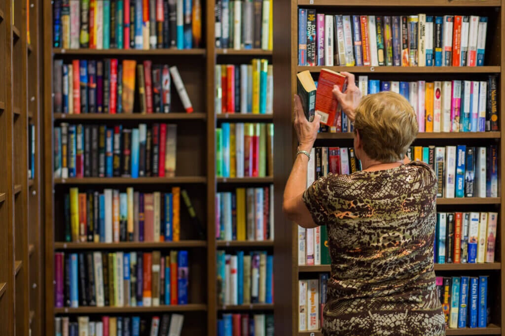 Resident putting a book on the bookshelf at Rolling Greens Village