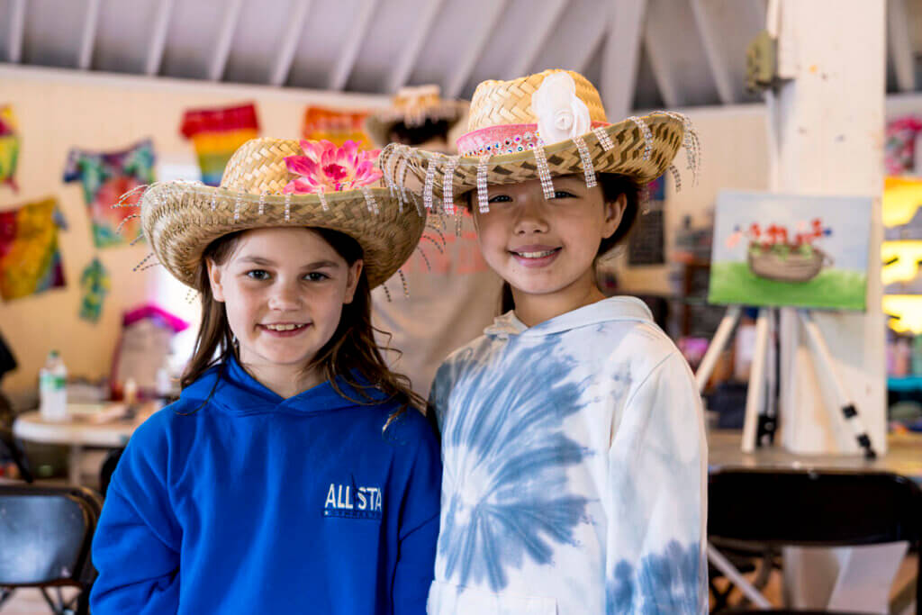 Two little girls showing off their cowboy hats they crafted at Point Sebago Resort.