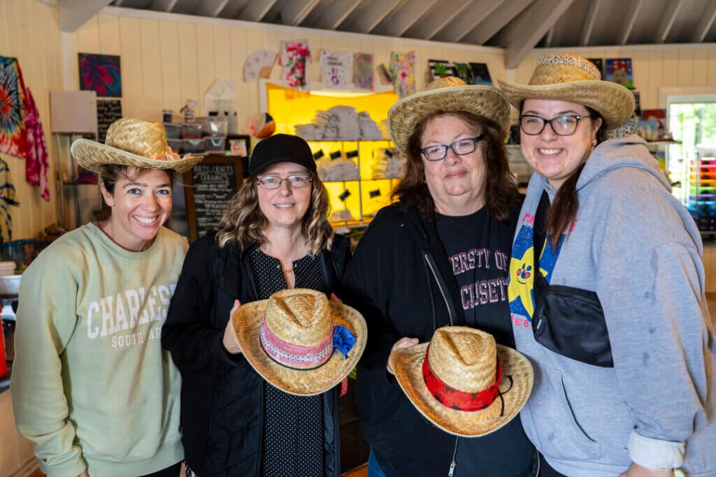 Four women showing off their cowboy hats they crafted at Point Sebago Resort.