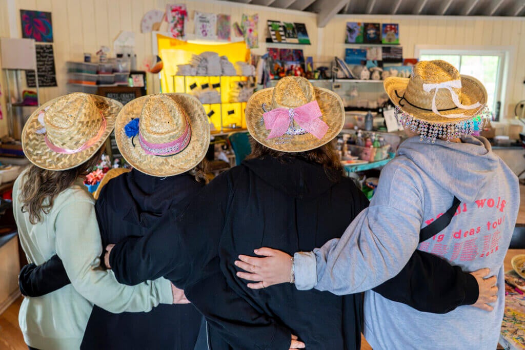 Four women showing off their cowboy hats they crafted at Point Sebago Resort.