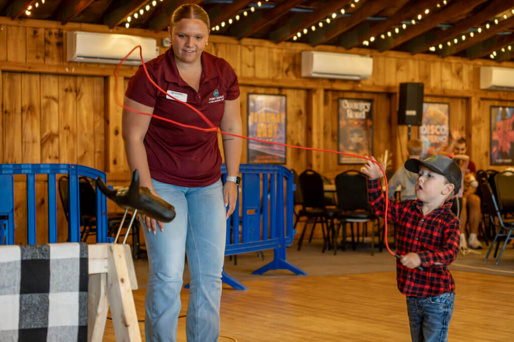 Little boy swinging his lasso around a fake cow during Country Western Weekend at Point Sebago Resort in Maine.