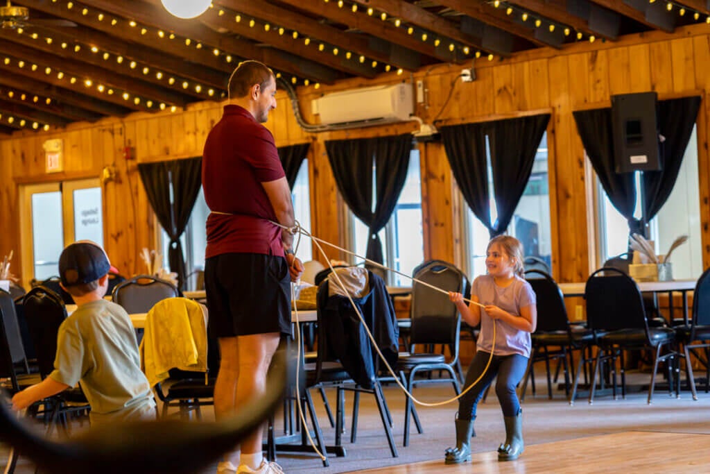 A little girl roping her lasso around a Point Sebago Resort team member during Country Western Weekend.