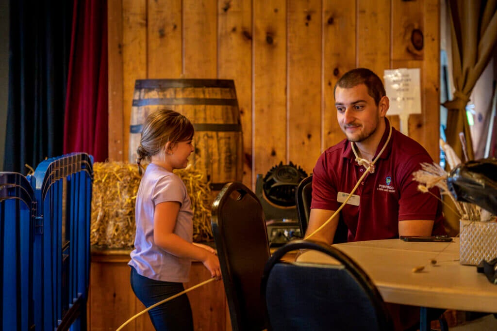 A little girl roping her lasso around a Point Sebago Resort team member during Country Western Weekend.