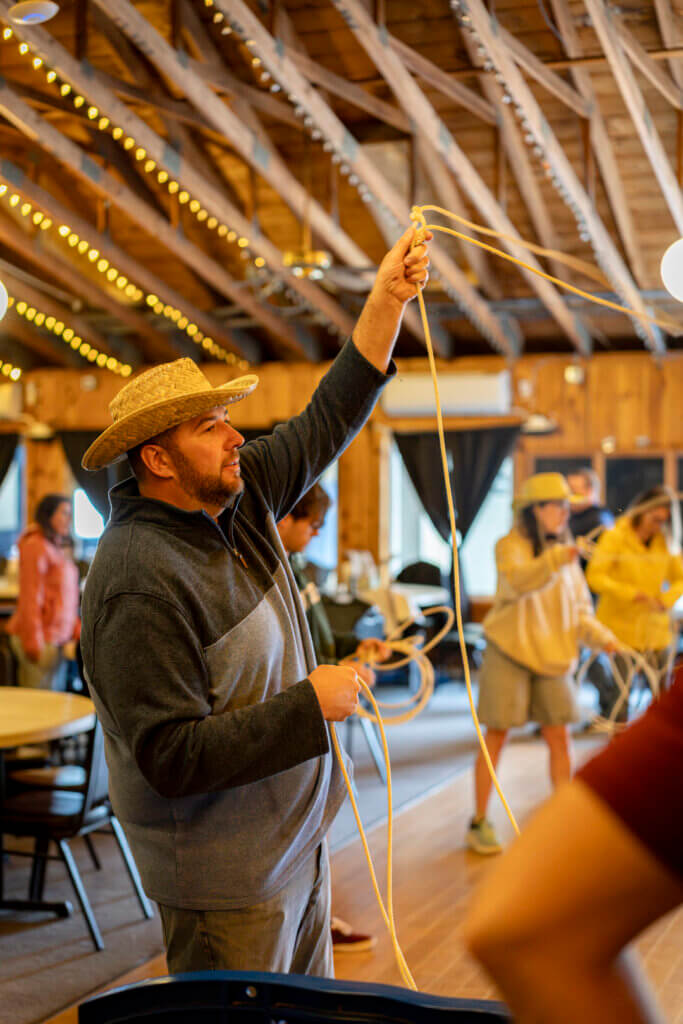 A man learning to lasso at Point Sebago Resort during Country Western Weekend.