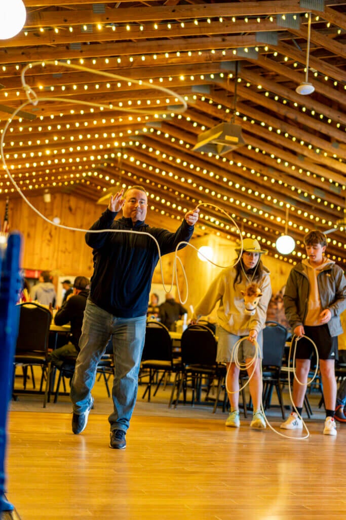 A man learning to lasso at Point Sebago Resort during Country Western Weekend.