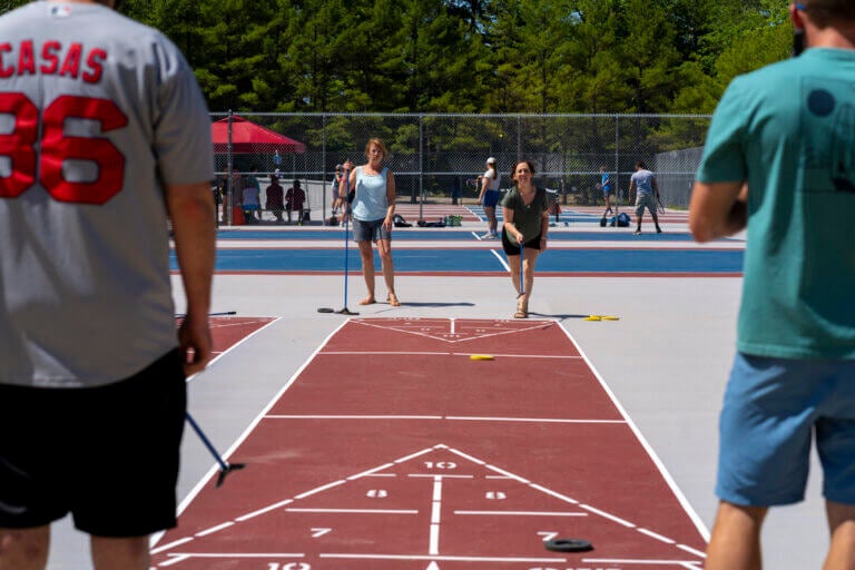 Guests playing shuffleboard on the newly resurfaced sports courts at Point Sebago Resort in Casco, Maine.