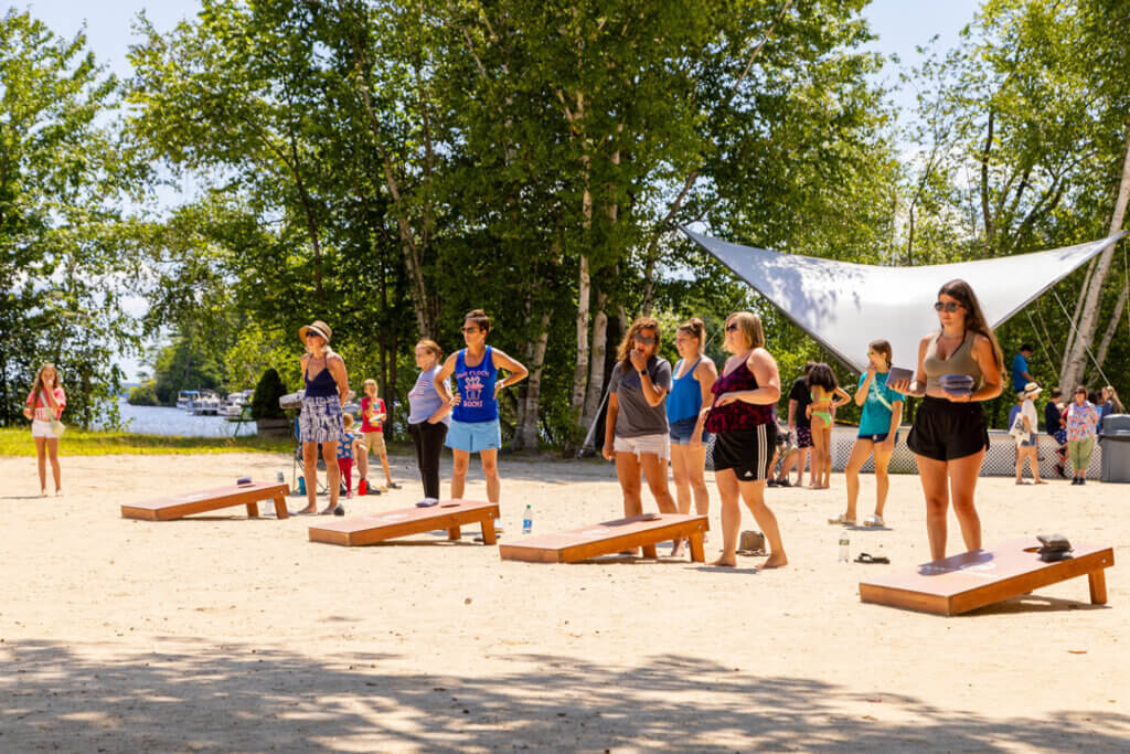 Point Sebago Resort guests enjoying cornhole acitivity on the beach