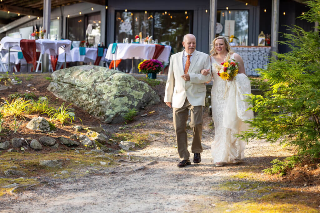 Bride being walked down the aisle at Point Sebago Resort in Casco, Maine. Photo by Life in Focus.