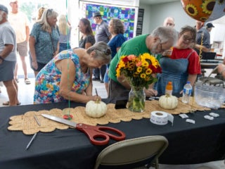 Residents at the welcome table filling out raffle tickets at the west clubhouse reopening on October 15, 2025.