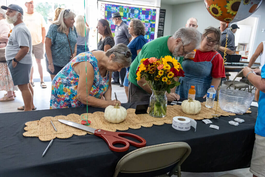 Residents at the welcome table filling out raffle tickets at the west clubhouse reopening on October 15, 2025.