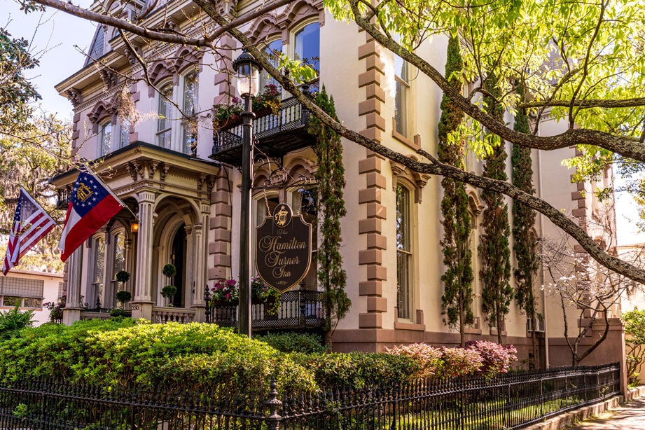 Savannah, GA - US - Mar 23, 2026 The historic Hamilton-Turner Inn stands elegant beneath leafy branches, showcasing ornate Victorian details, wrought iron, and Southern charm.