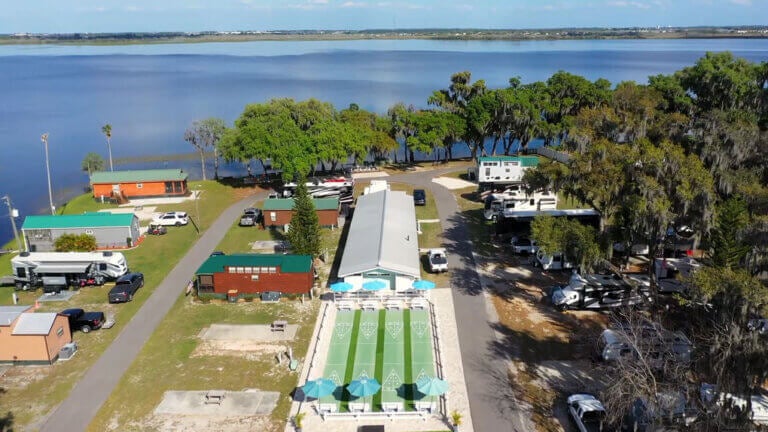 An aerial view of Oak Harbor RV Park showing RV sites, the shuffleboard court, and Lake Lowery in Florida.