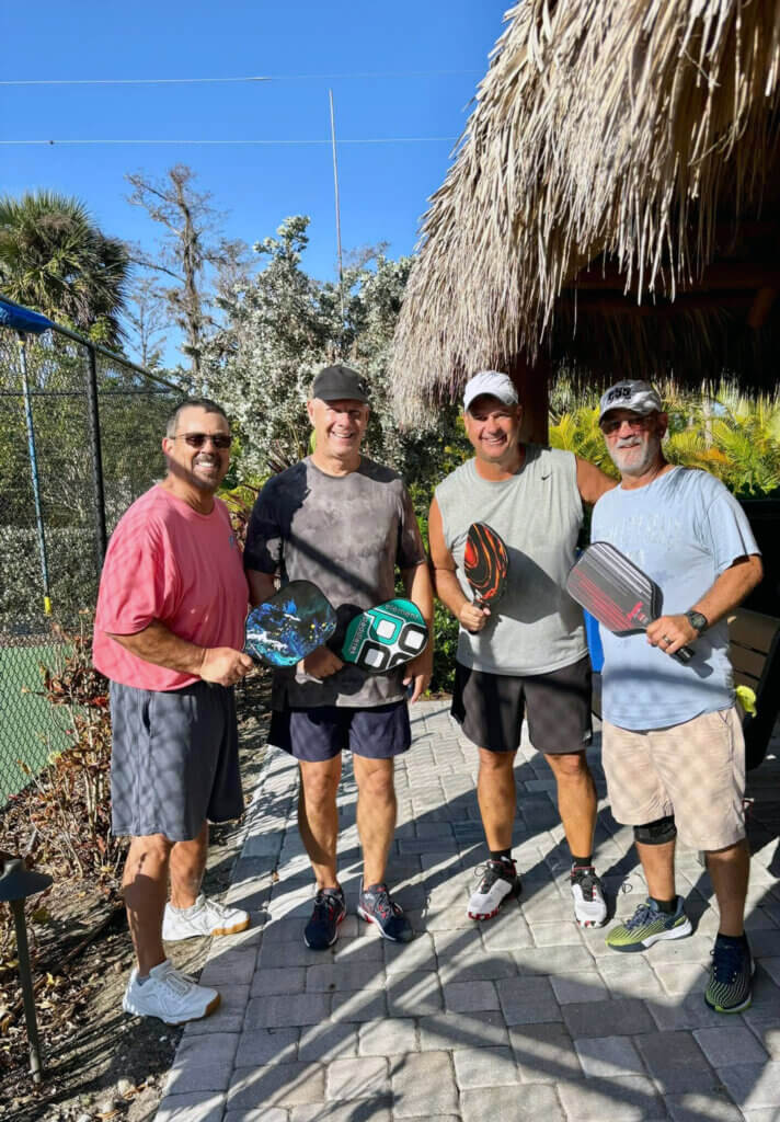Male guests at Blueway standing in front of pickleball courts with their paddles
