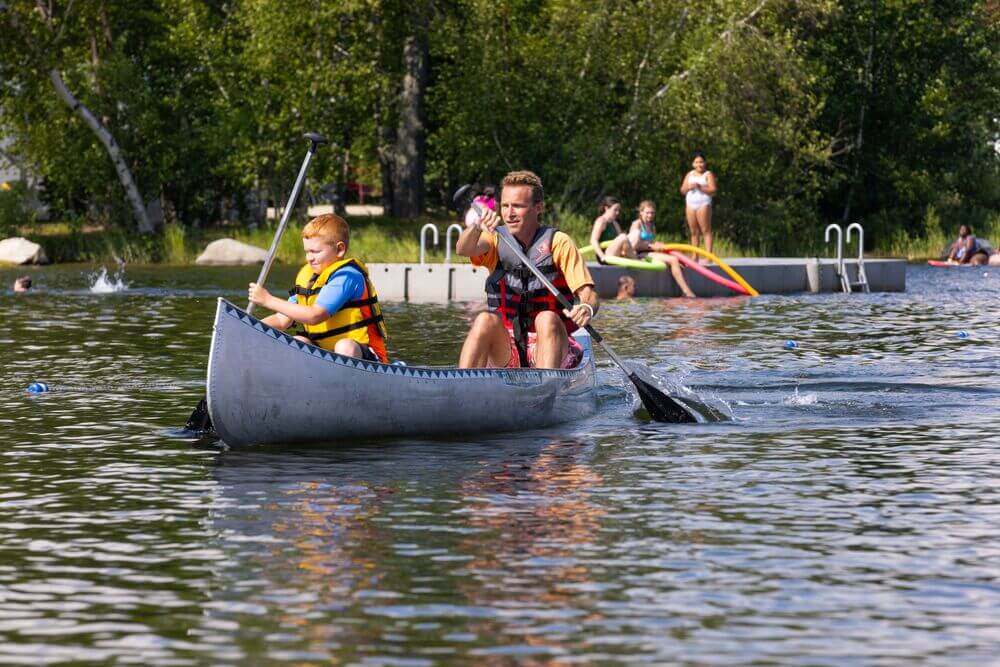 Father and son in a canoe race on Sebago Lake at Point Sebago Resort in Maine.