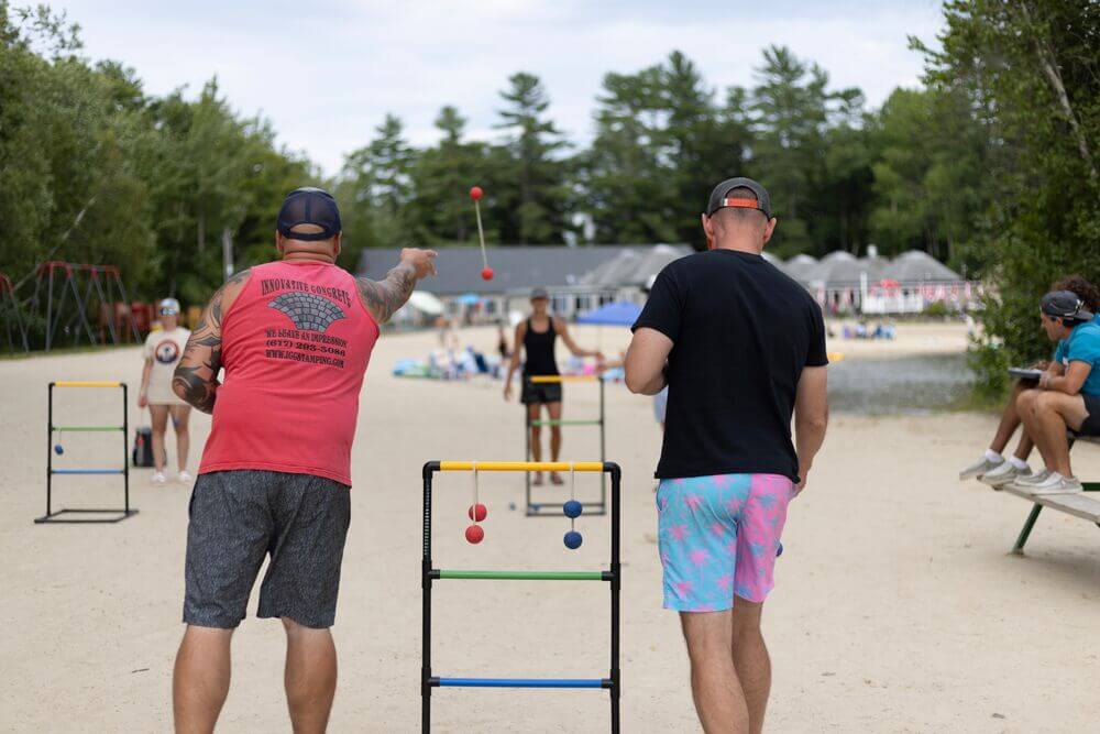 Men playing ladder toss at Point Sebago Resort on the beach.