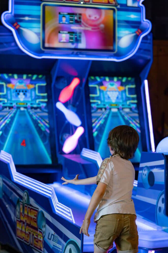 Kid playing an arcade game at Point Sebago resort.
