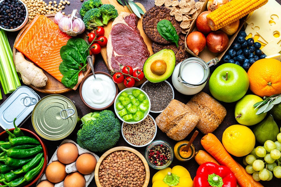 A spread of apples, oranges, lemon, grapes, pears, celery, tomatoes, onions, corn, garlic, broccoli, steak, salmon, ginger, carrots, grains, fruits, and vegetables.