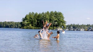 Kids tossing a boy into the air in Sebago Lake in Maine.