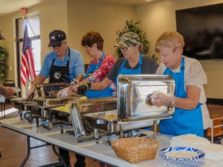 Members of Veterans Club at The Meadows in Tarpon Springs, FL, serving food at a club event.