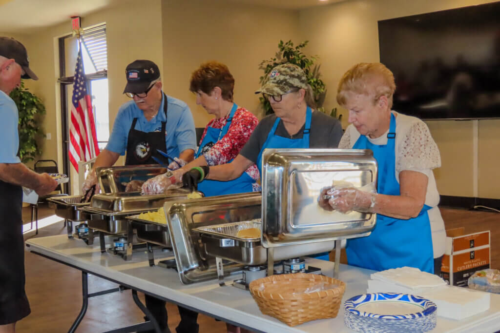 Members of Veterans Club at The Meadows in Tarpon Springs, FL, serving food at a club event.