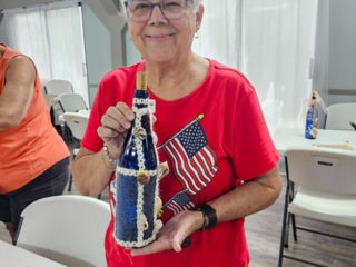 Residents with their decorated blue glass bottle creations from a craft class at Holiday RV Park in Leesburg, FL.