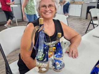 Residents with their decorated blue glass bottle creations from a craft class at Holiday RV Park in Leesburg, FL.