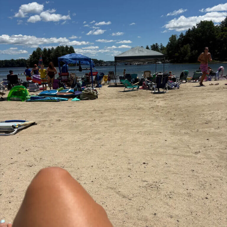 View of Sebago Lake from the Point Sebago beach covered in tents.
