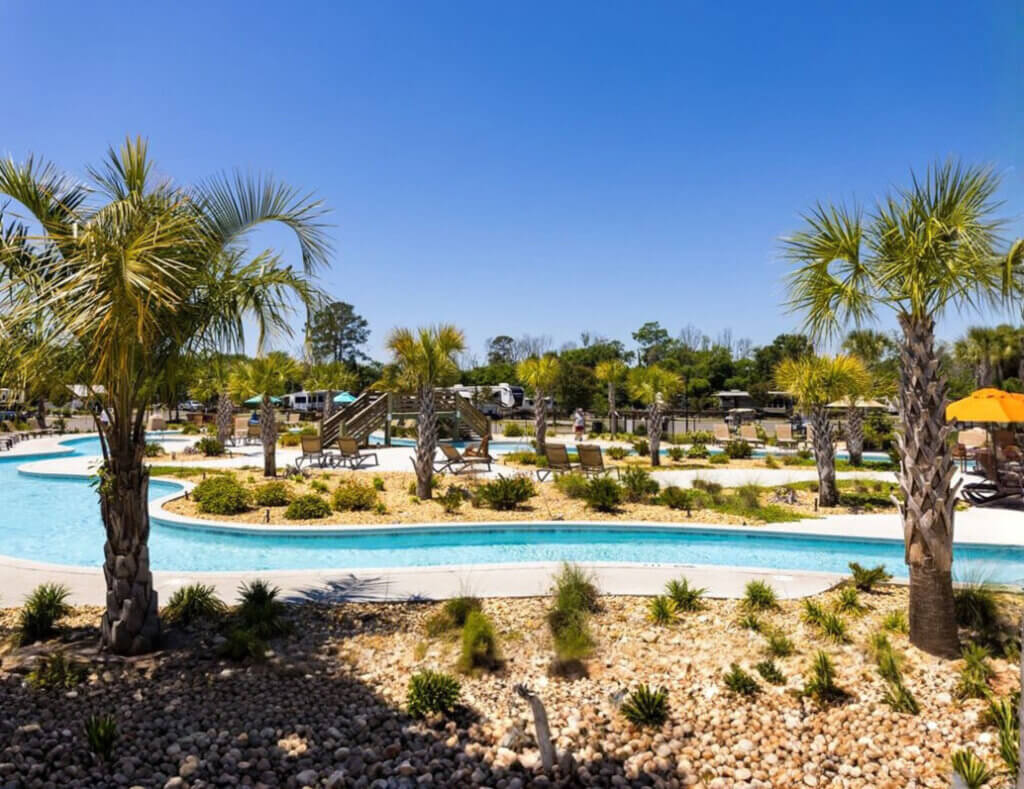 Lazy river with palm trees and umbrellas at CreekFire RV resort in Savannah, GA.