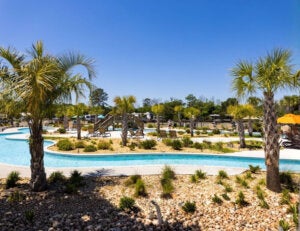 Lazy river with palm trees and umbrellas at CreekFire RV resort in Savannah, GA.