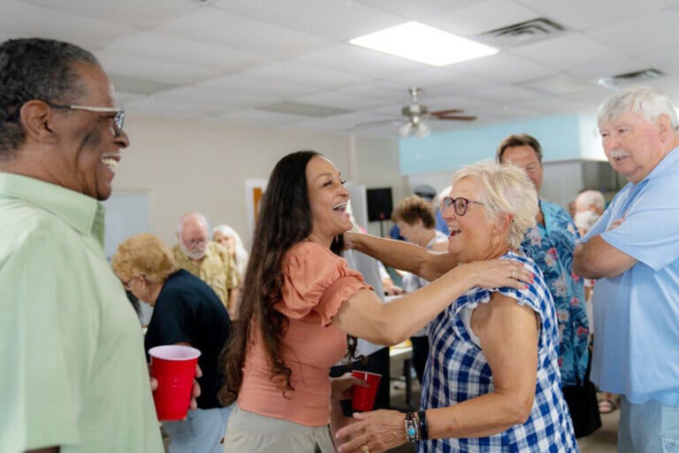 Women hugging at an RV resort potluck at River Vista RV Park.