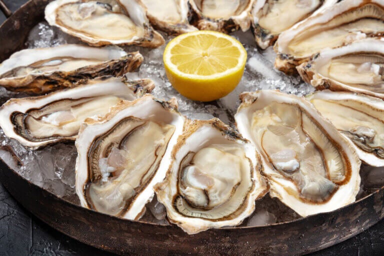 A tray of oysters with a half-cut lemon in the center.