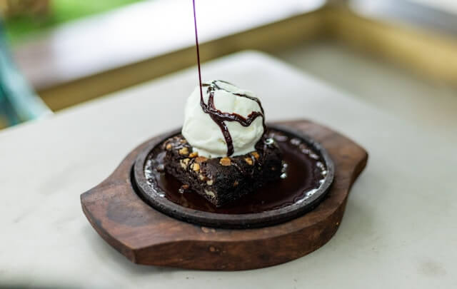 Brownie fudge sundae topped with ice cream in a wooden dish.