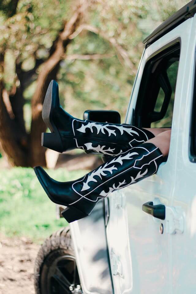 Black and white boots hanging out of a white jeep window.