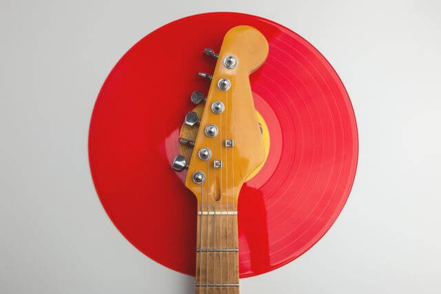 Electric guitar laying on a red record