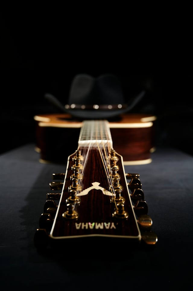 Black cowboy hat on top of an acoustic guitar.