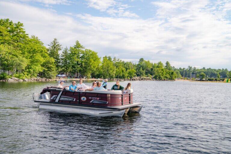 A pontoon boat full of people on Sebago Lake in Maine.