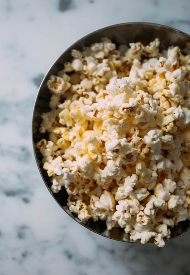 A bowl of movie theatre butter popcorn on a marble countertop