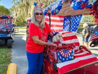Resident and her dog with a decorated golf cart for the 4th of July parade at Holiday RV Park in Leesburg, Florida.